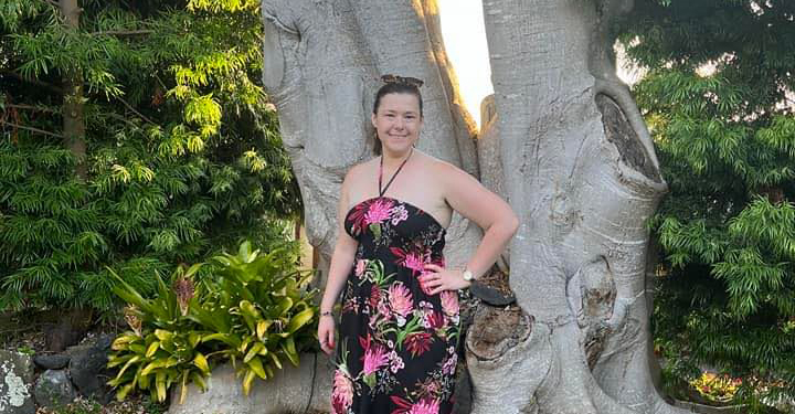 Allie Steele standing in a sundress in front of a tree